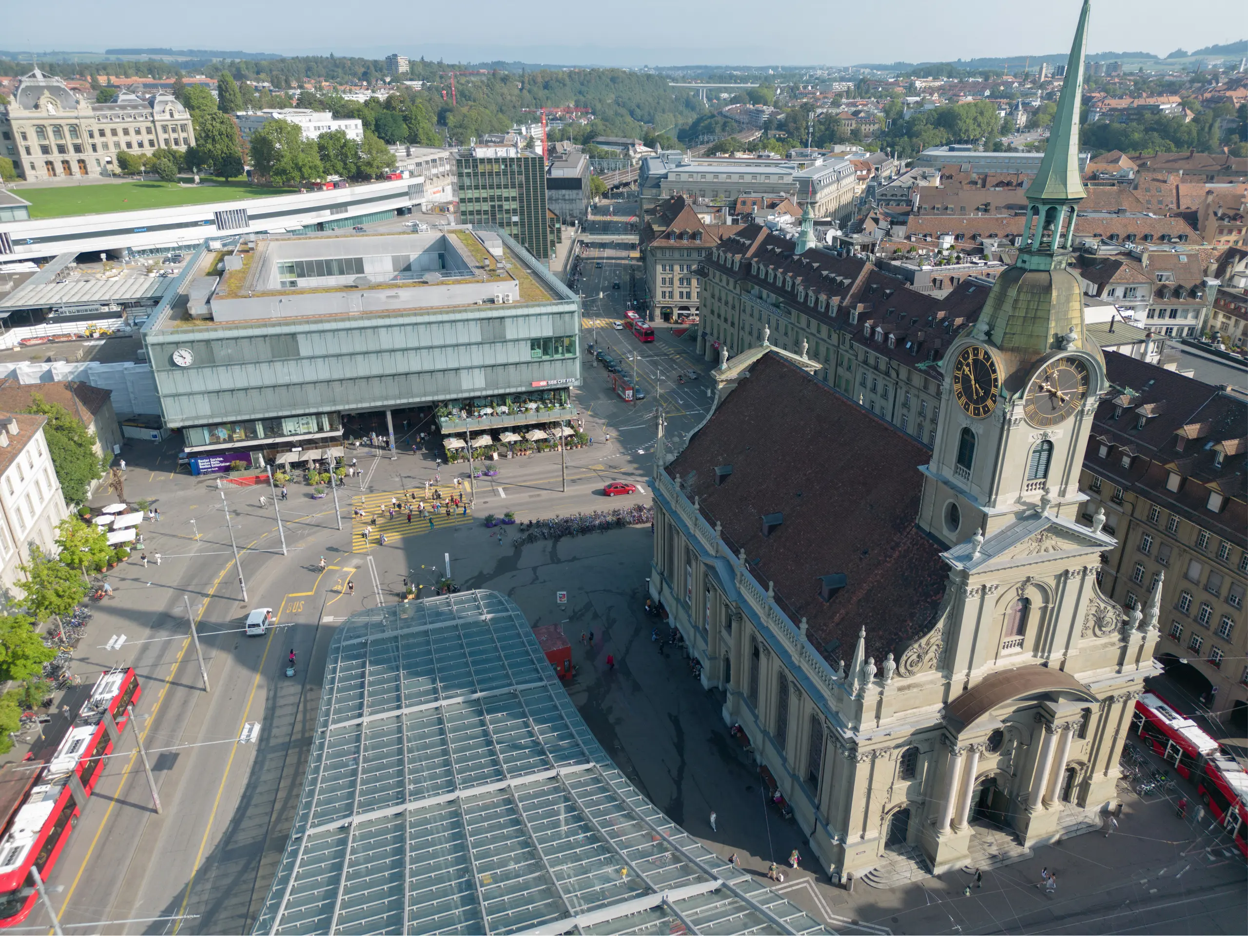Luftaufnahme des Bahnhofsplatzes in Bern mit dichtem Verkehr, Straßenbahnen und urbaner Infrastruktur im Jahr 2025.