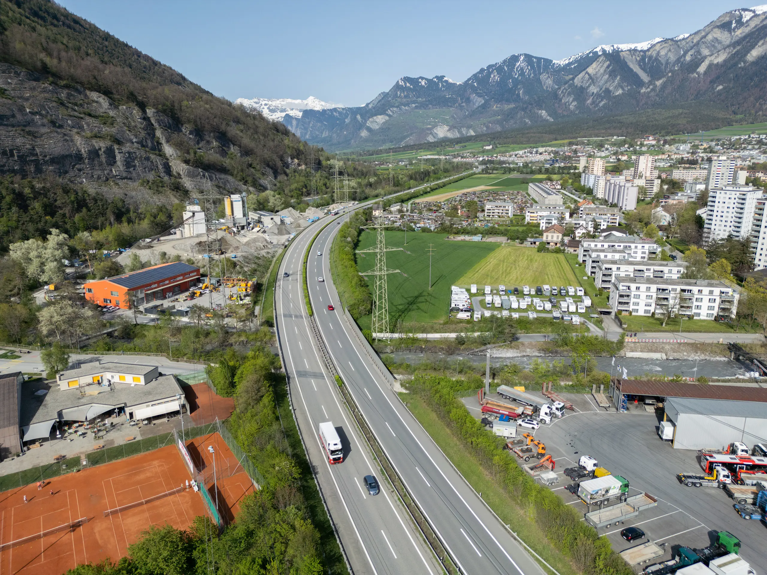 Luftaufnahme der Autobahn in Chur mit angrenzenden Wohngebieten, Industrieanlagen und einer klassischen Verkehrsinfrastruktur.