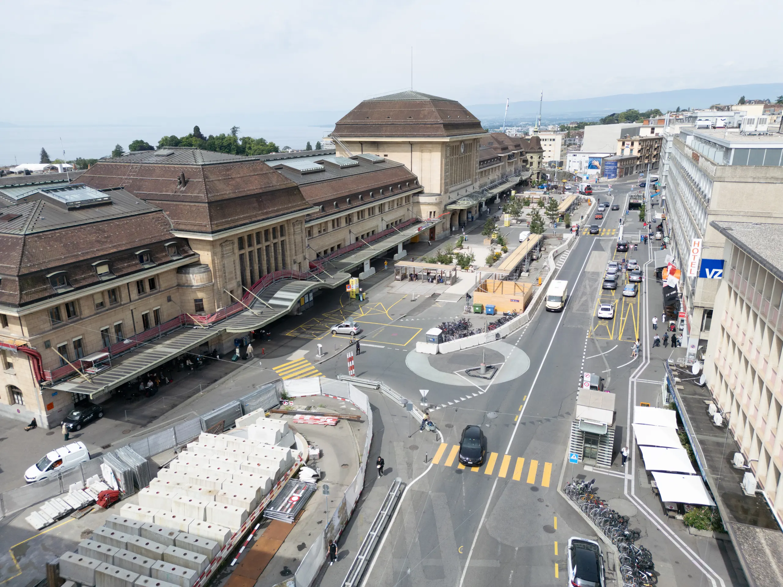 Luftaufnahme des Bahnhofs Lausanne mit Straßen, Fahrzeugen und Bauarbeiten, die die aktuelle Infrastruktur der Stadt zeigen.