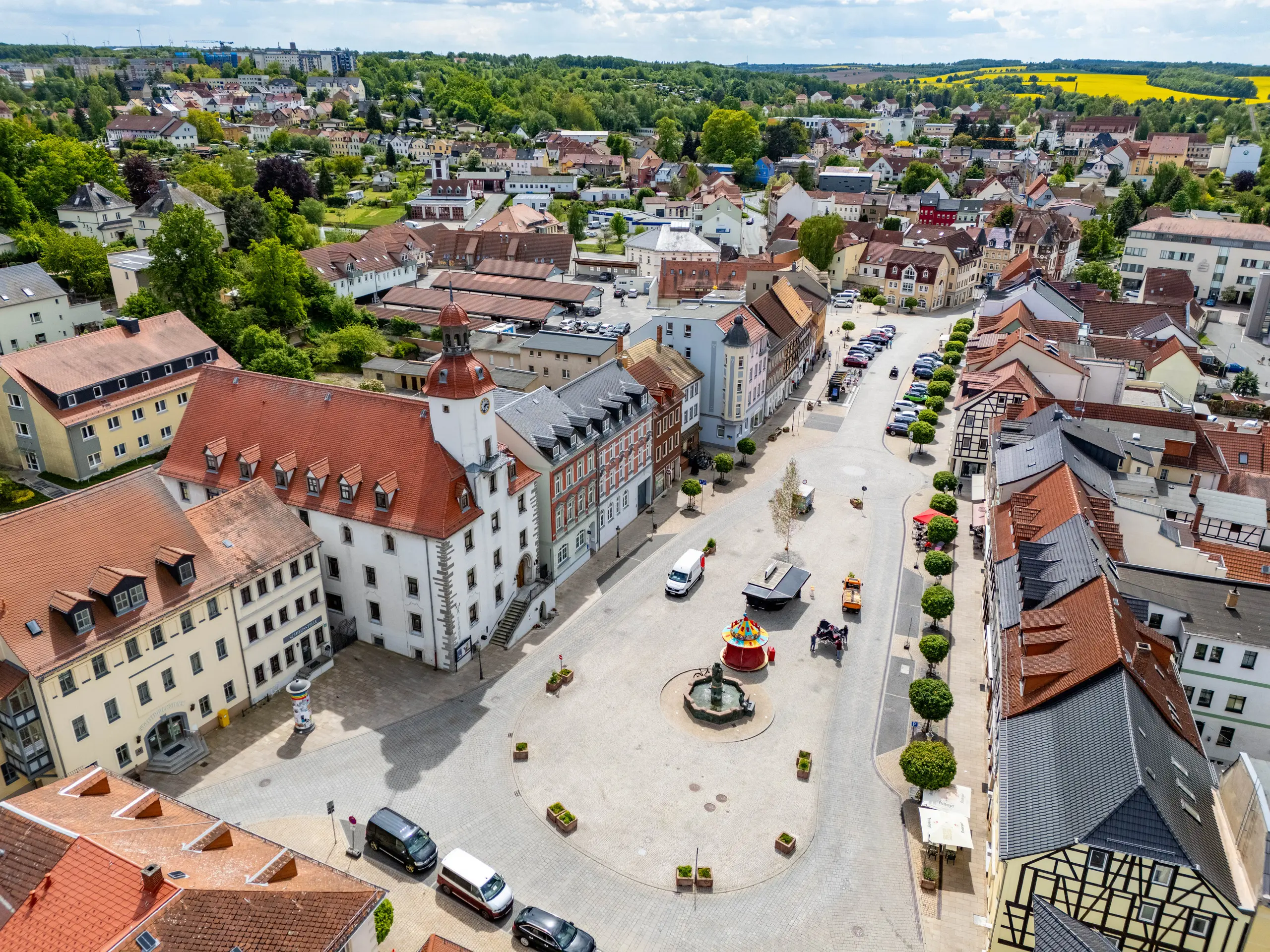 Luftaufnahme des Marktplatzes in Schmölln 2025 – historisches Rathaus, umliegende Wohn- und Geschäftshäuser, parkende Autos und klassischer Stadtplatz.