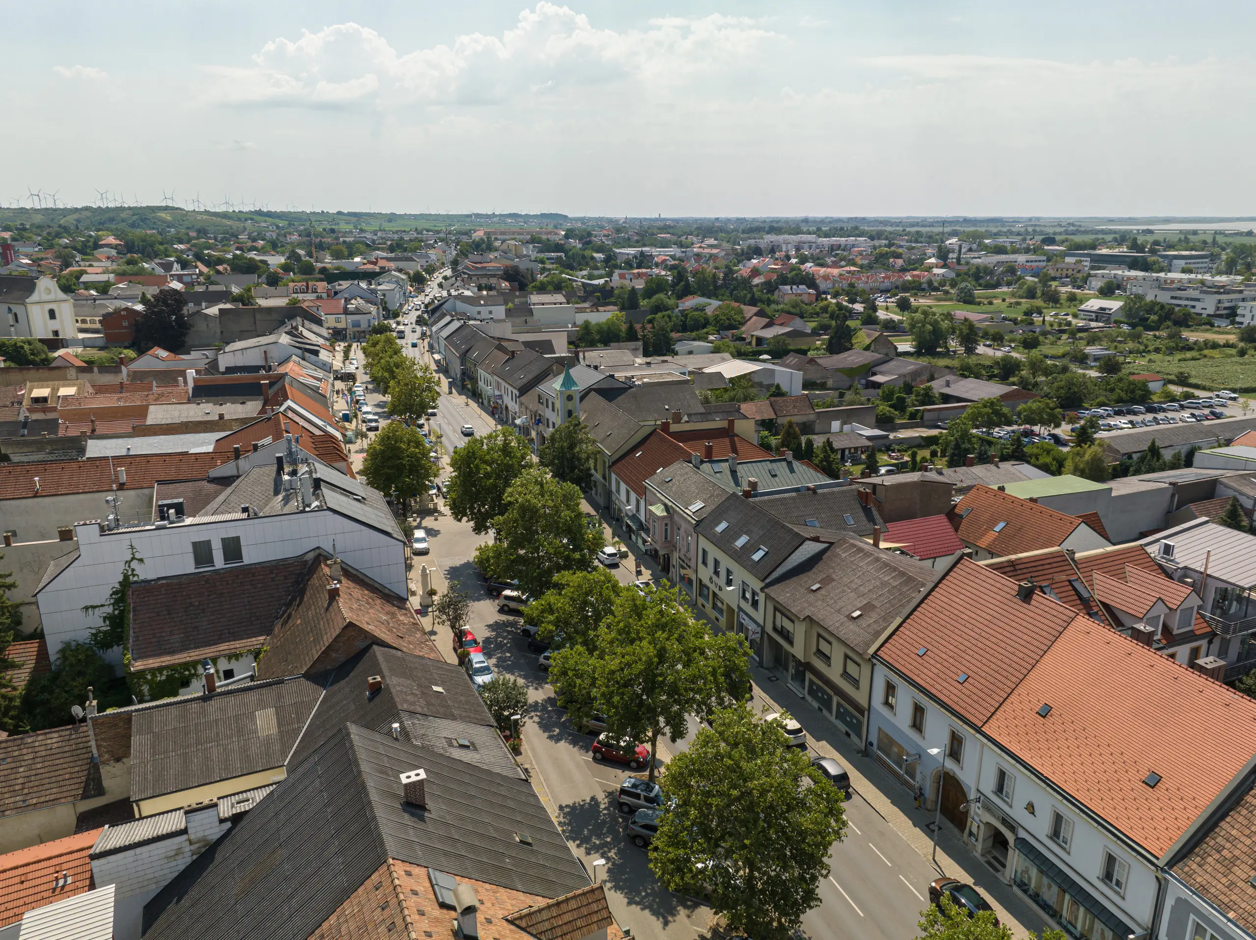 Luftaufnahme des Stadtzentrums von Neusiedl am See 2025 – klassische Hauptstraße mit Wohn- und Geschäftshäusern, Autoverkehr und begrenzten Grünflächen.